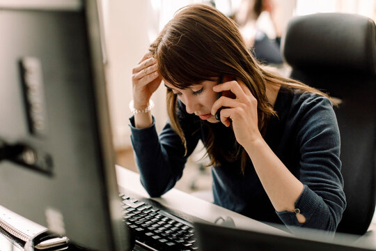 Computer programmer talking on phone at workplace