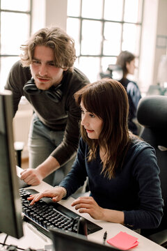 Male and female professionals discussing coding in office