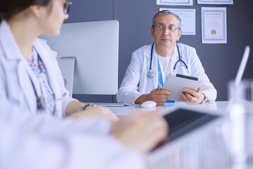 Serious medical team using a laptop in a bright office