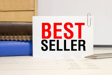 BEST SELLER text on the business card written in red marker near the keyboard on a blue background