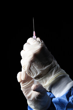 Mano con guantes quir&uacute;rgicos sosteniendo jeringa para inyectar. Manos de enfermera sosteniendo jeringa de 5cc. Preparando inyecci&oacute;n