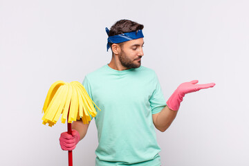 young man feeling happy and smiling casually, looking to an object or concept held on the hand on...