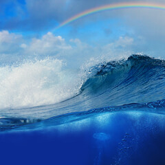 ocean view cloudy sky with colourful rainbow and breaking surfing wave splitted to two parts by...
