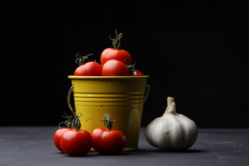 Tomates Cherry recien cosechados en canasta amarilla junto a cabeza de ajo