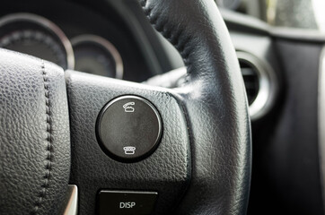 Close up of the answer and reject phone buttons on the steering wheel with black leather cover in a...