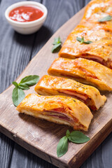 Pizza roll stromboli with cheese salami olives and tomatoes