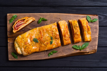 Pizza roll stromboli with cheese salami olives and tomatoes