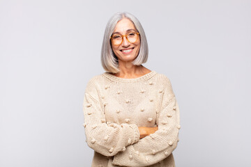 gray haired woman looking like a happy, proud and satisfied achiever smiling with arms crossed