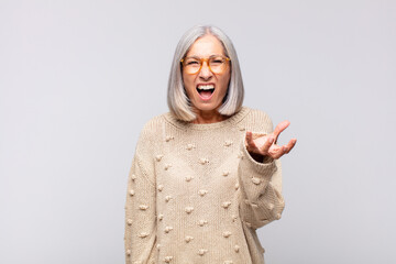 gray haired woman looking angry, annoyed and frustrated screaming wtf or what‚Äôs wrong with you