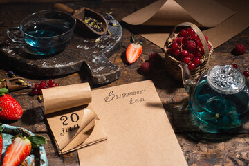 Berry still life. Berries, tea, pen, calendar, notebook on an old brown wooden table, top view