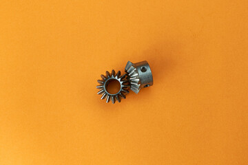 Bevel gears on an orange background, top view. Automotive or gear cutting industry.