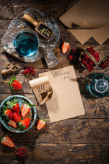 Obraz na płótnie Canvas Berry still life. Berries, tea, pen, calendar, notebook on an old brown wooden table, top view