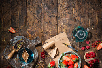 Berry still life. Berries, tea, pen, calendar, notebook on an old brown wooden table, top view