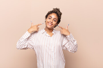 young afro woman smiling confidently pointing to own broad smile, positive, relaxed, satisfied...