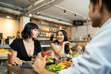 Group of people sitting in indoor restaurant cafe eating food together