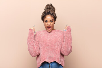 young afro woman feeling horrified and shocked, raising hands to head and panicking at a mistake