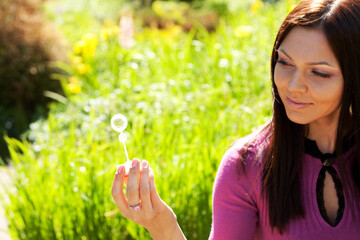 girl blow soap bubble against a background grass