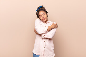 young afro woman feeling in love, smiling, cuddling and hugging self, staying single, being selfish...