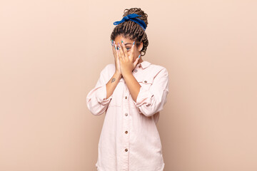 young afro woman feeling scared or embarrassed, peeking or spying with eyes half-covered with hands