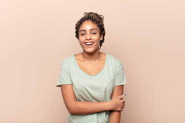 young afro woman laughing shyly and cheerfully, with a friendly and positive but insecure attitude