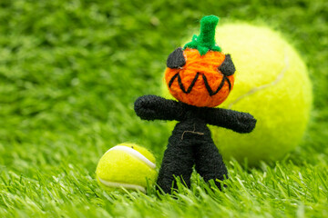 Tennis ball on Halloween day with ghost and tennis ball on green grass background