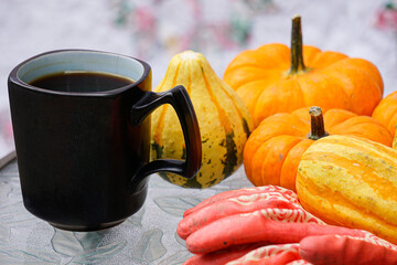 Pumpkin, gourds, gardening gloves, and coffee on a table in front of a quilt.