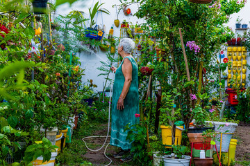 Mulher idosa cuidando de jardim florido