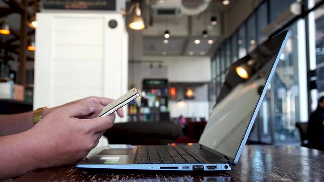 Man hand holding cellphone making online payment with credit card,  typing cvv number for paying on tablet at cafe, shopping online. 