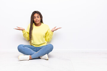 young afro woman feeling puzzled and confused, doubting, weighting or choosing different options...