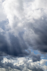 Fototapeta na wymiar Dramatic clouds. Bright sunlight shines through the rain clouds. Autumn - spring weather. Vertical photo