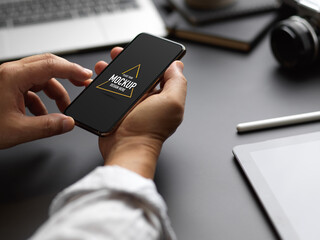 Male entrepreneur using mock up smartphone on black worktable