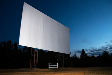 Blank white drive-in movie screen; rural outdoor setting