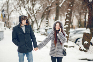 Cute couple walking in a winter city. Elegant woman in a gray fur coat