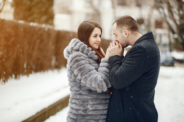 Cute couple walking in a winter city. Elegant woman in a gray fur coat