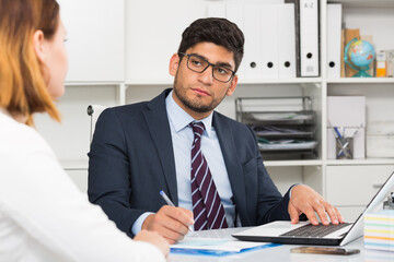 Successful businessman in glasses talking to female colleague in office