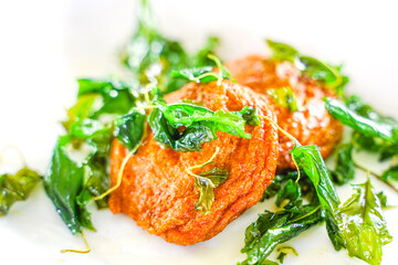 close up of fried fish patty or fried fish paste ball (tod mun pla) with crispy basil leaf on top on white background