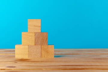 Stacked wooden blocks on wooden desk against blue background