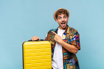 young man feeling joyful and surprised, smiling with a shocked expression and pointing to the side....