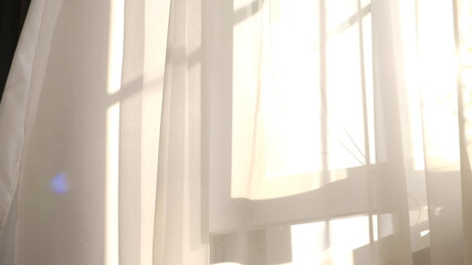 wind blows through the open window in the room. Waving white tulle near the window. Morning sun lighting the room, shadow background overlays.