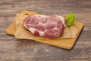 Raw pork steak over wooden board