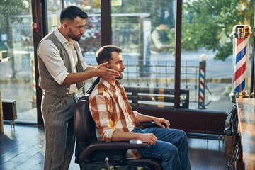 Professional barber adjusting head positioning of his client