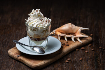 Ice Cream with vanilla coffee. Coffee Frappe with shell on the dark old wooden table. Coffee beans. Glass on the white plate. Irish coffee.