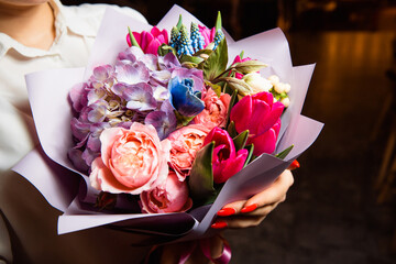 The girl holds in her hand a magnificent bouquet with multi-colored fresh flowers. A great gift for any occasion.