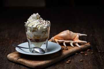 Ice Cream with vanilla coffee. Coffee Frappe with shell on the dark old wooden table. Coffee beans. Glass on the white plate. Irish coffee.