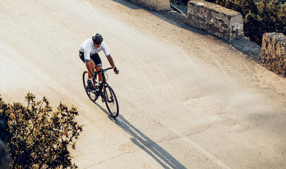Naklejka premium Professional cyclist on a mountain road at sunrise