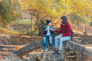 mother with little kid resting at autumn city public park