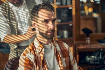 Fototapeta premium Serious barbershop client waiting for his barber to cut his hair