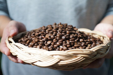 Man holds in hands wattled basket with roasted coffee beans