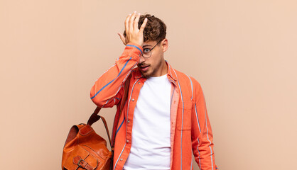 young man raising palm to forehead thinking oops, after making a stupid mistake or remembering,...