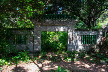 Naklejka premium Chinese gateway at entrance to abandoned house in park in China